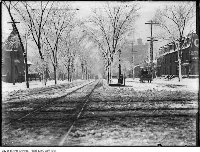 Toronto Winter Photographs Spadina Avenue, looking south from Queen Street. - Febraury, 1914 - photograph. The railings at centre denote the entrance to the underground public lavatory.