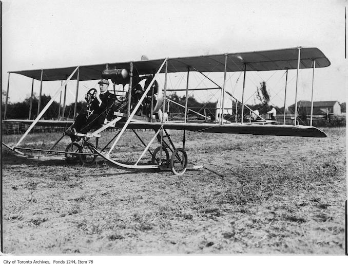 J.A.D. McCurdy sitting in airplane. - 1911 - photograph of a man sitting in an airplane. Information provided by a researcher indicates that the man is probably J.A.D. McCurdy in a bi-plane with 7-cylinder Gnome rotary engine, and that the event is probably either the Ontario Aviation Meet held at Donlands Farm, Todmorden Mills, August 3-5, 1911, or the Aviation Meet, Hamilton, July 27-29, 1911.