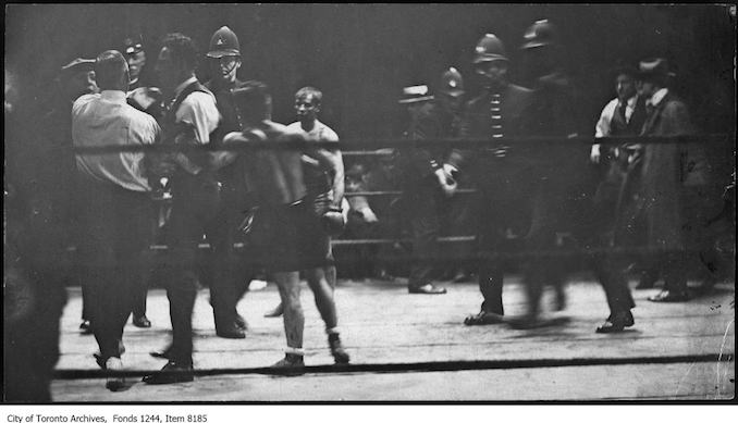 Police go into the ring to protect referee Lou Marsh (left) at Patsy Wallace vs. Jimmy Wilde boxing match at CNE. - May 24, 1920