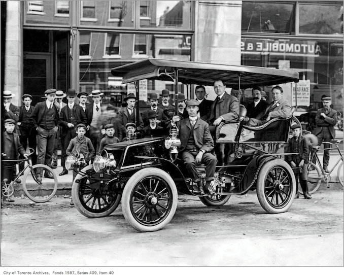 men in auto with group of on-lookers, on Temperance St., across from the Automobile and Supply Co. Ltd., 22-26 Temperance St 1902