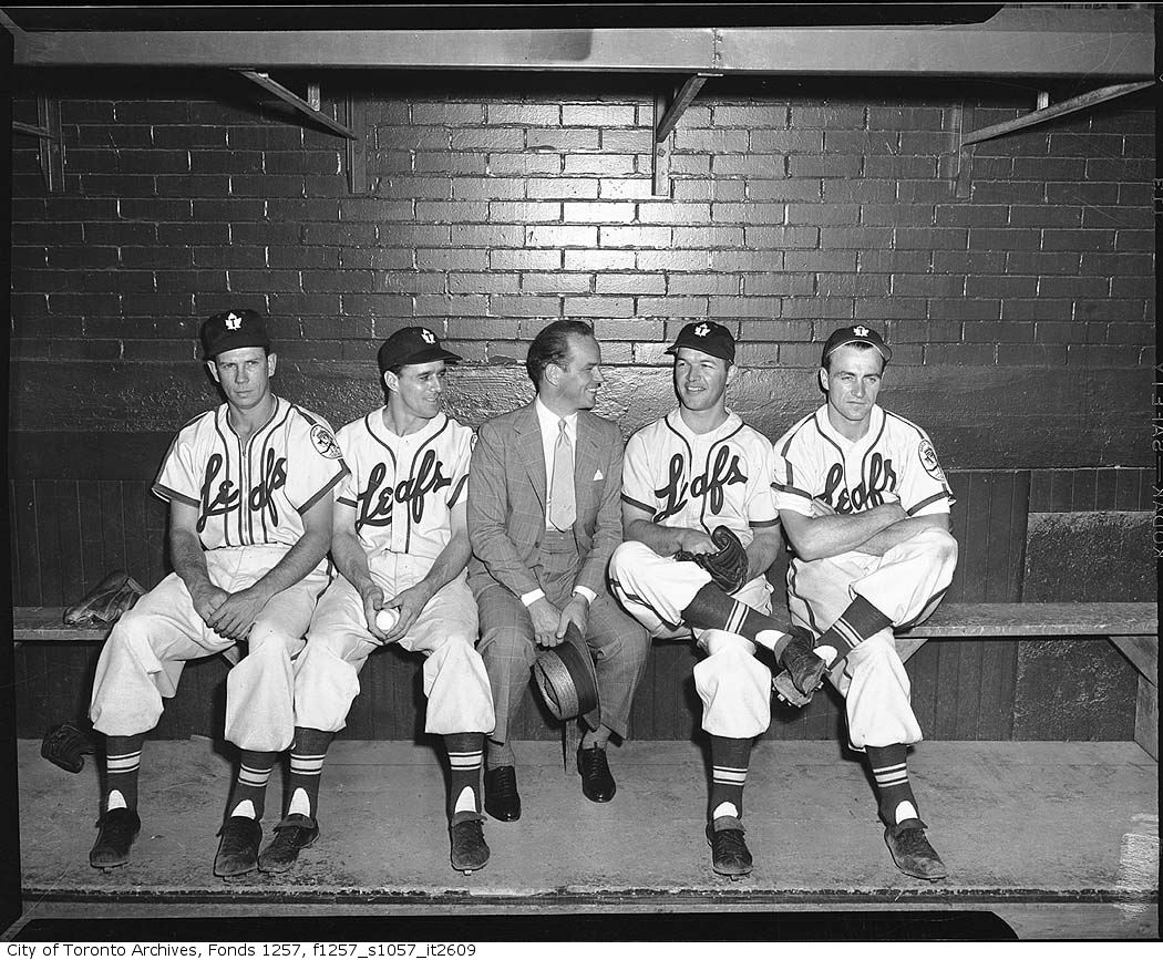 Jack Kent Cooke with baseball players in Toronto Maple Leafs Baseball Club dugout, Maple Leaf Stadium 195?