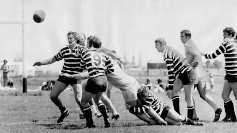 1974 - Touring English rugby team from Somerset (striped shirts) have situation well in hand as ball squirts loose during exhibition game against Ontario side at Fletcher Field