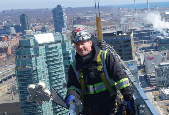 glazier outside on swing stage replacing windows in the sky