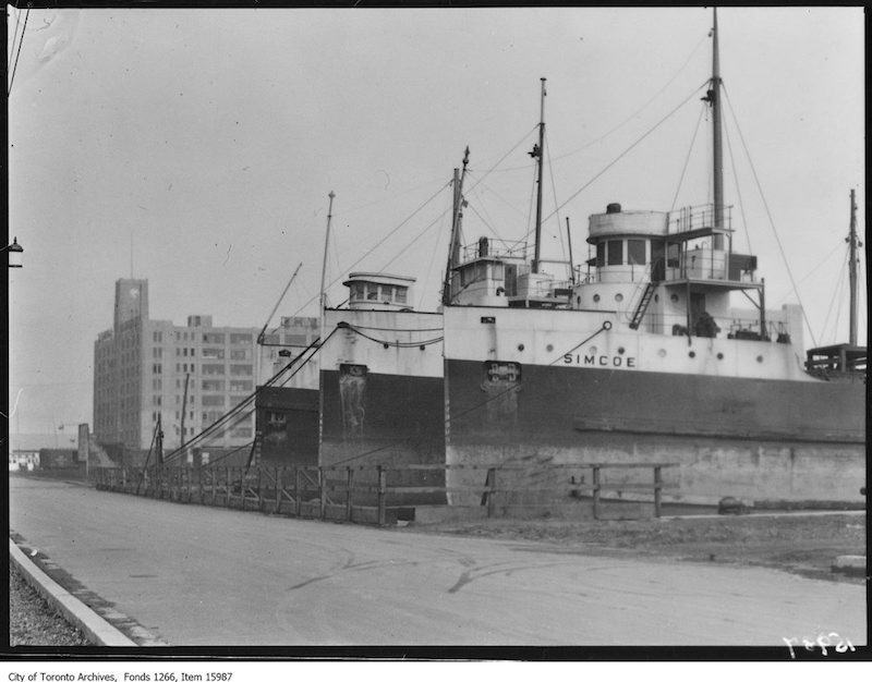 1929 - Waterfront, line of boats and warehouse in background