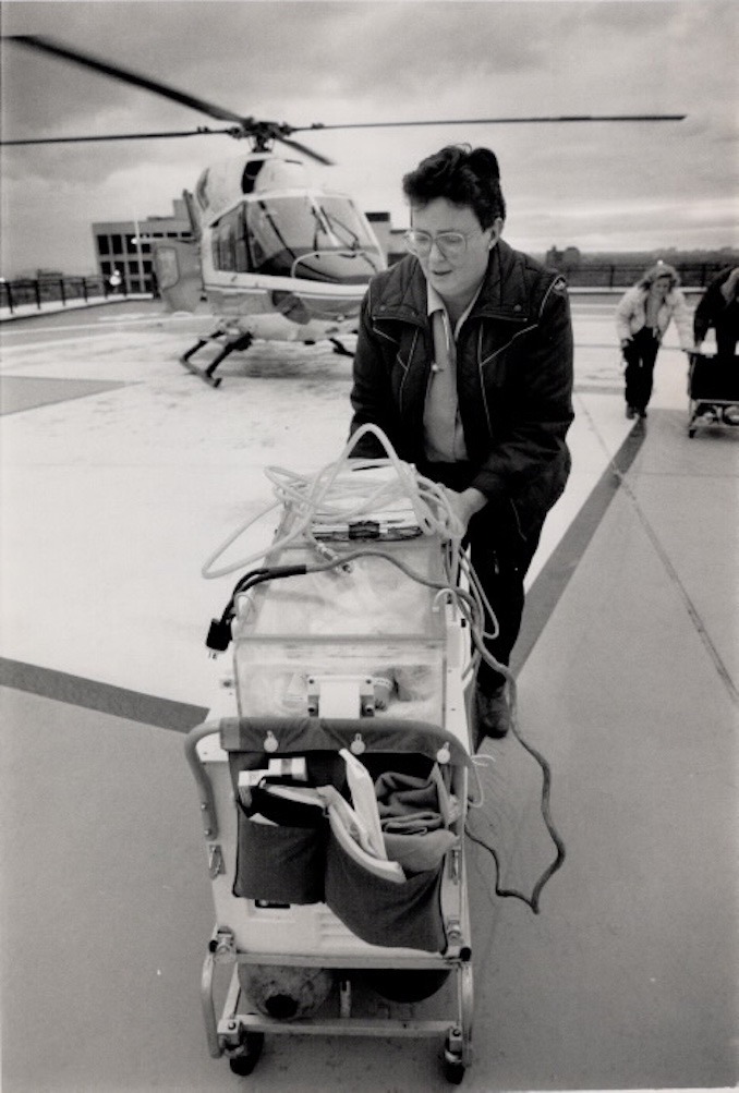 1988 - Sharon Noriss; who accompanied a premature baby being transported from Oshawa; rolls the incubator across the rooftop. Below; from left; are pilots Alex Gontier & Porus Dinshaw; paramedic Steve Deuchars & ambulance attendant Scott Andrews