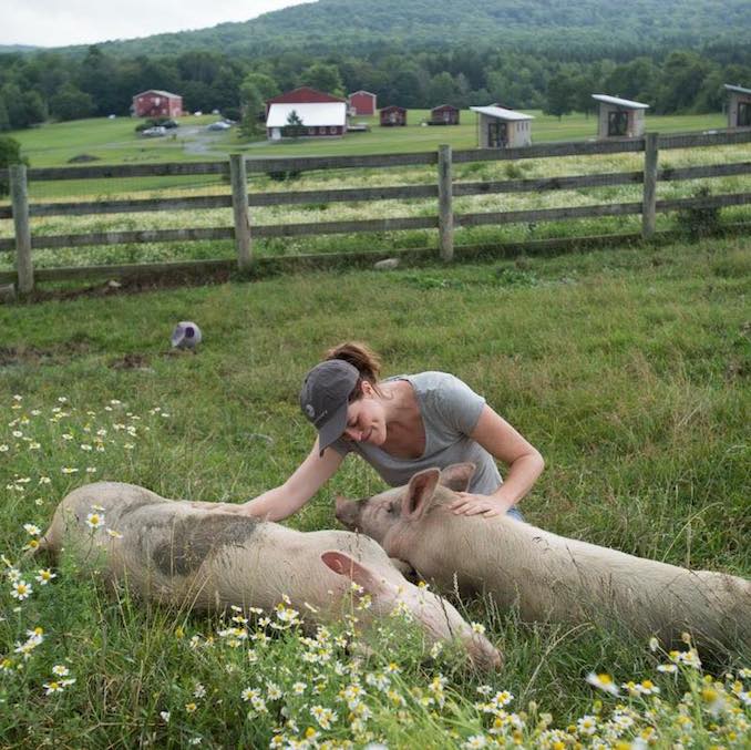 Kelly spends some time connecting with pigs at Farm Sanctuary in between shoots.