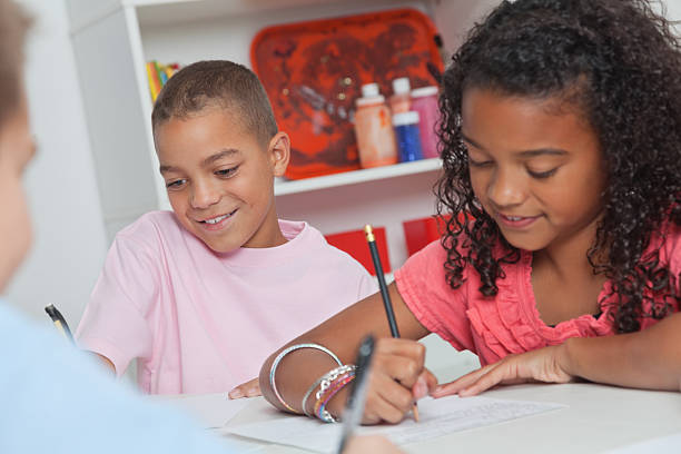 Happy elementary students writing in class. - Toronto Guardian