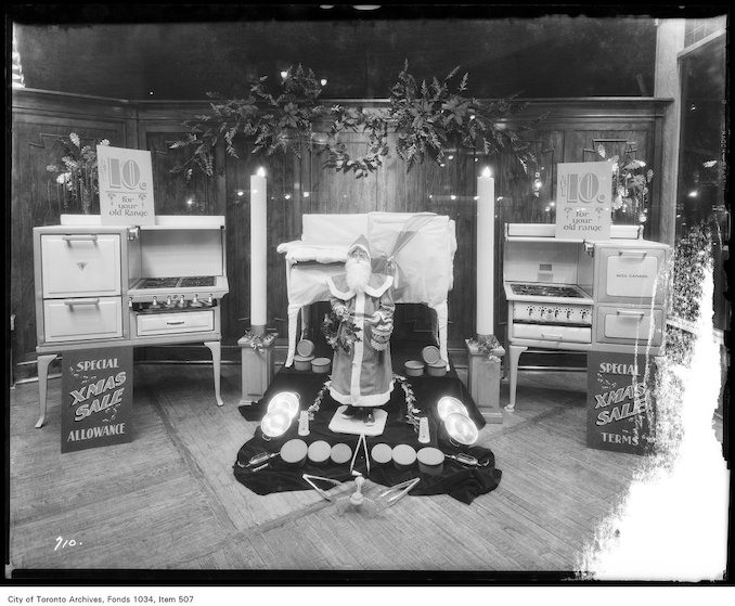 1930-Christmas display of gas ranges with Father Christmas surrounded by cooking utensils