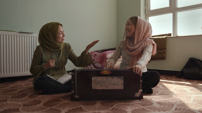 Sadiqa Madadgar and Zahra Elham practicing music and laughing with one another