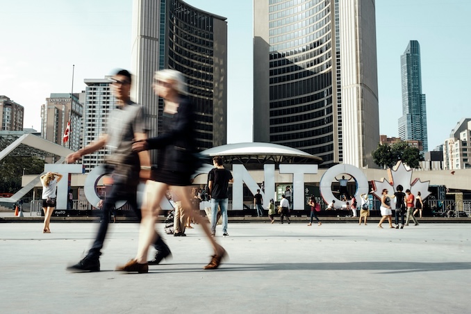 people walking in front of the Toronto sign in Toronto, Canada.