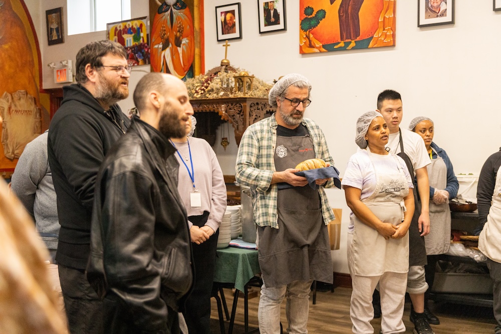 Father Nicolaie (far left), guests and staff say some words before they eat lunch at Saint John's Mission