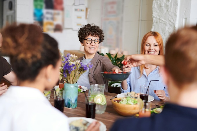 Middle aged women sharing a meal over a dinner table.