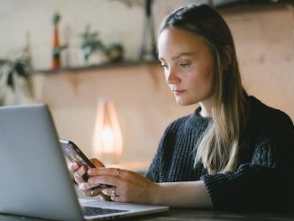 Woman using smartphone in front of her laptop for featured image