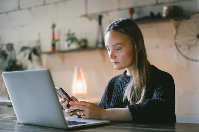 Woman using smartphone in front of her laptop