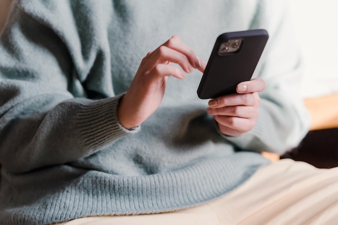 Woman using a cell phone wearing a blue sweater