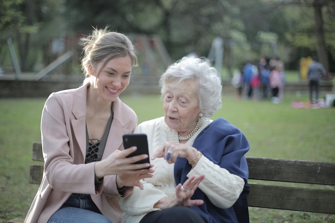 Woman showing an elderly woman her cellphone