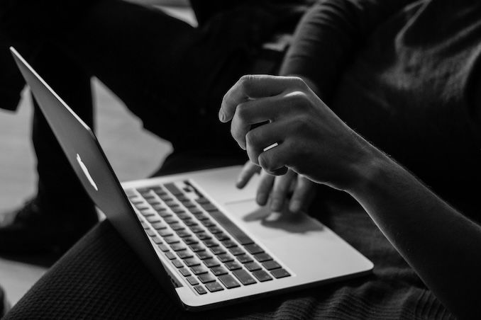 black and white image of a close of of someone using a laptop computer.