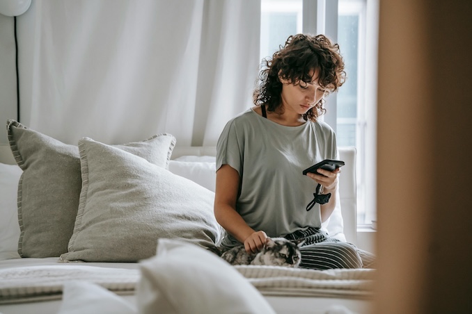 Woman on her bed using a cell phone