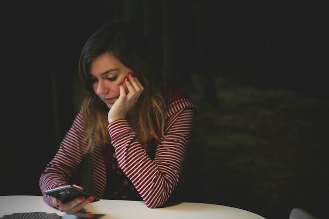 Woman on her phone looking concerned - The ultimate guide to common scams: How they work & how to stay safe