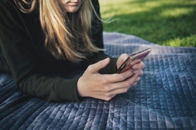 Woman texting on her cell phone in a park.