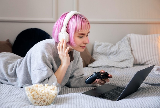 woman on her bed on the laptop with headphones.