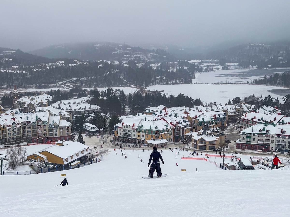 Mont Tremblant view on the hill looking at the village. Snow covered mountains and snowborders and skiers in the foreground.